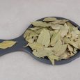 Dried green bay leaves on a wooden platter. High quality photo